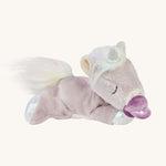 The baby unicorn toy is lying down, with a magnetic dummy stuck to its mouth