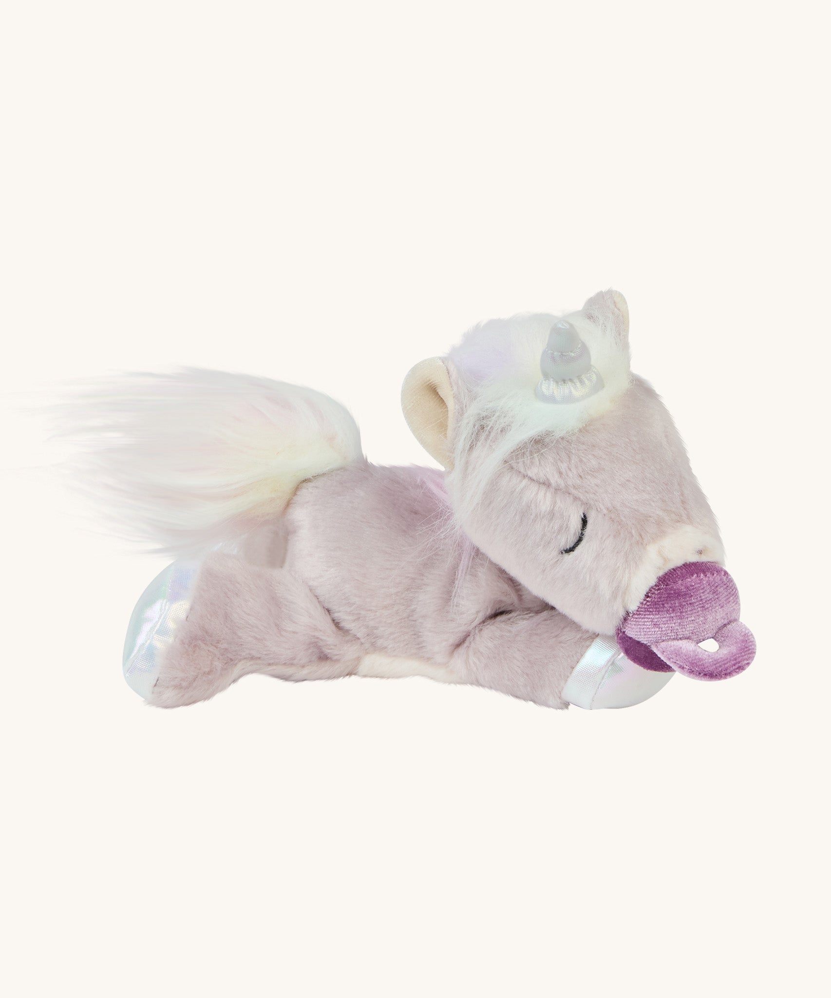 The baby unicorn toy is lying down, with a magnetic dummy stuck to its mouth
