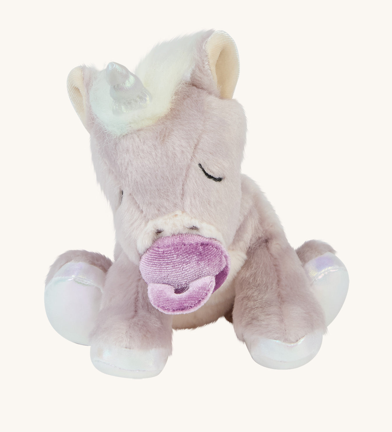 The baby unicorn toy is positioned to sit upright, and is holding the magnetic dummy