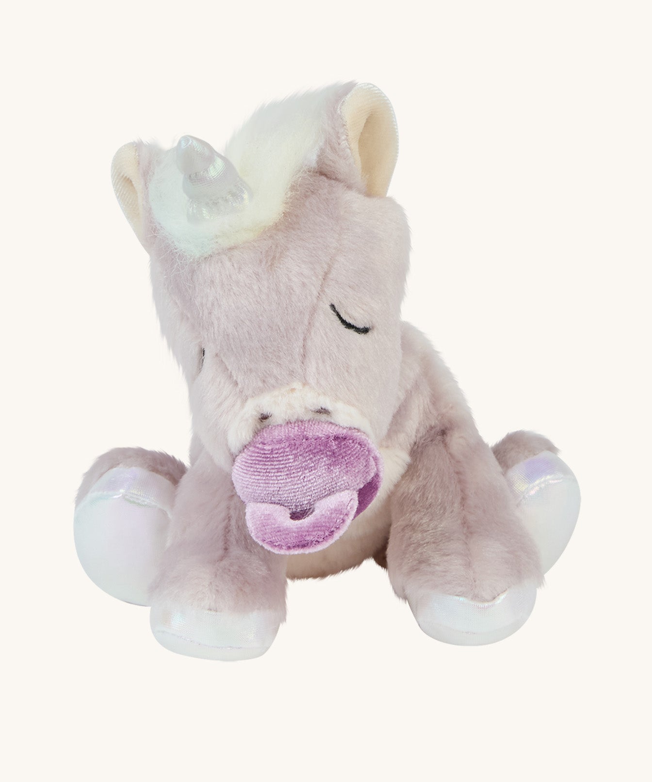 The baby unicorn toy is positioned to sit upright, and is holding the magnetic dummy