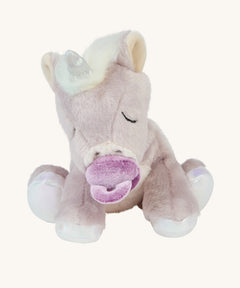 The baby unicorn toy is positioned to sit upright, and is holding the magnetic dummy