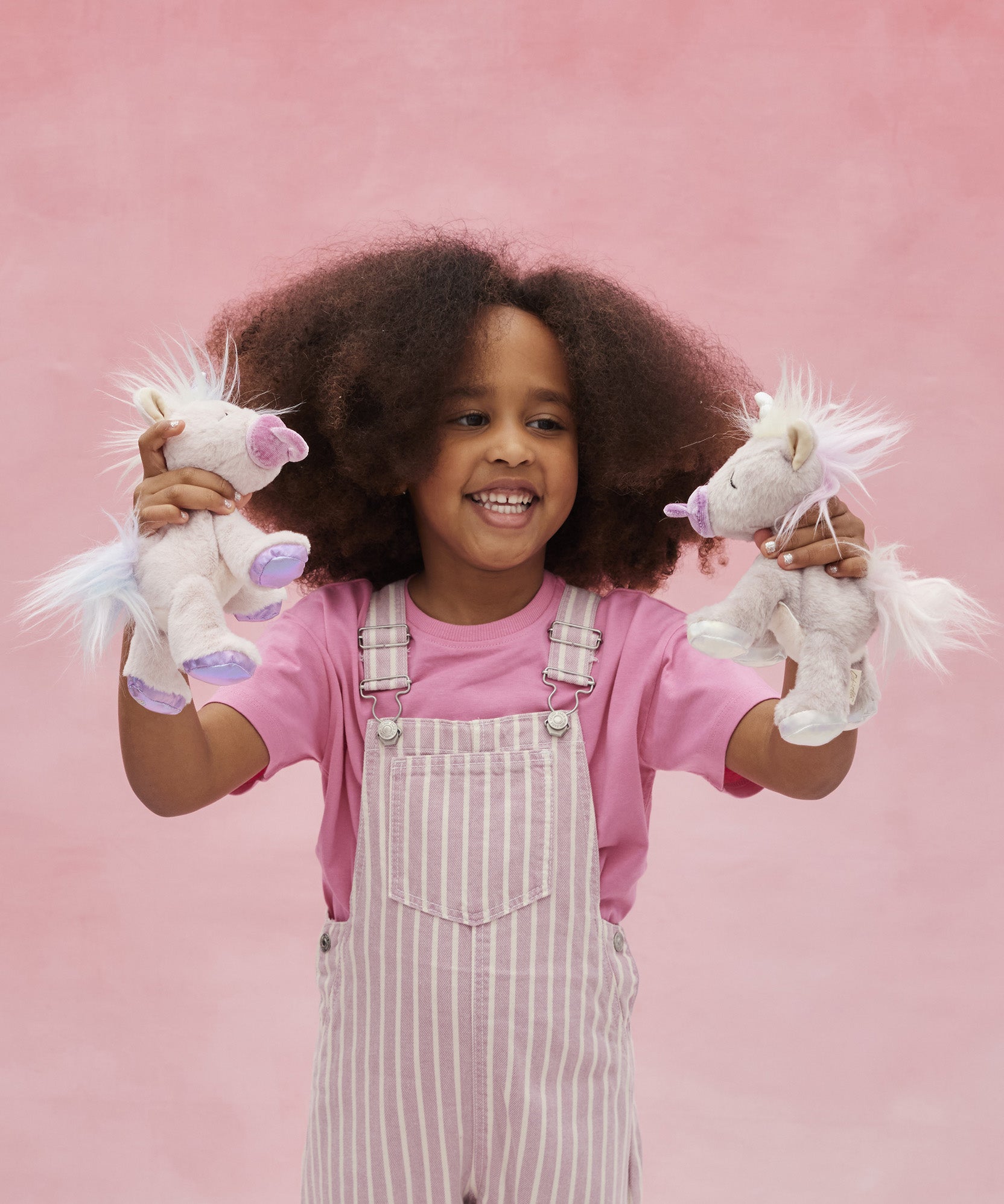 Child playing with both the pink and lilac baby unicorn toys