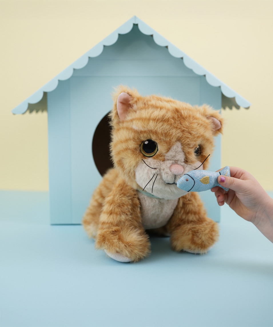 A close up of a child's hand holding the magnetic blue fish in front of the Olli Ella Koda dinkum cat doll available at Babipur