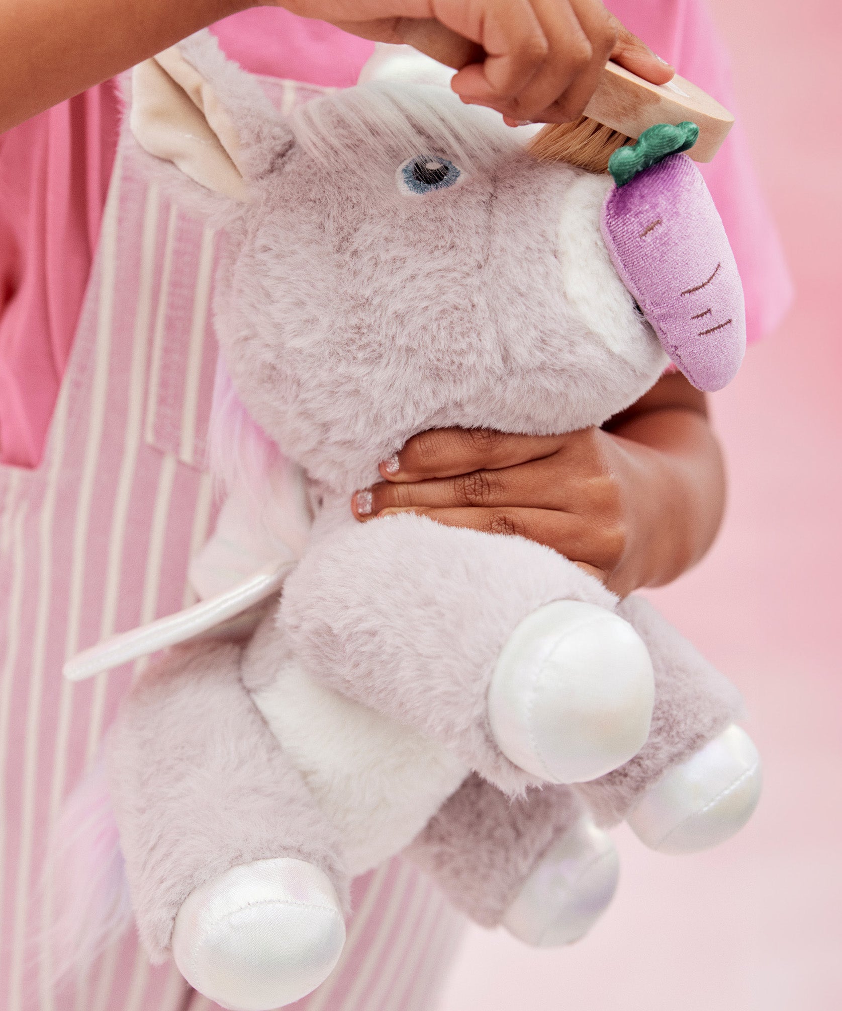 A child pretends to feed the unicorn toy with the carrot