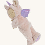 A pink fluffy Olli Ella unicorn doll lying on it's side on a cream background