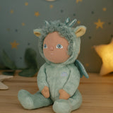 Olli Ella Dante the dinky dinkum dragon doll available at Babipur sitting on a wooden surface with a decorative starry background. 