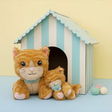 A Olli Ella Binx cat dinkum doll sitting next to koda the binky kitten doll with a cardboard shelter in the background. Both of these soft toy dolls are available at Babipur.