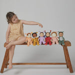 A little girl sat on a bench, with the Olli Ella Backyard Buddies Dinky Dinkum Dolls.