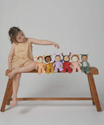 A little girl sat on a bench, with the Olli Ella Backyard Buddies Dinky Dinkum Dolls.