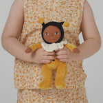 A little girl holding the Olli Ella Dinky Dinkum Doll - Billie Bumblebee - in a yellow onesie with a black hood and antennae, with a white ruffled collar, brown eyes, and buzzy bee wings.