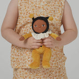 A little girl holding the Olli Ella Dinky Dinkum Doll - Billie Bumblebee - in a yellow onesie with a black hood and antennae, with a white ruffled collar, brown eyes, and buzzy bee wings.