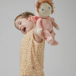 A little girl holding the Olli Ella Dinky Dinkum Doll - Millie Moth - with a peach coloured onesie, moth wings, curly ginger hair, and antennae.