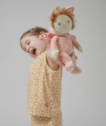 A little girl holding the Olli Ella Dinky Dinkum Doll - Millie Moth - with a peach coloured onesie, moth wings, curly ginger hair, and antennae.