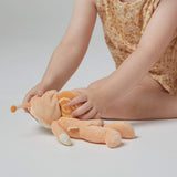 A little girl playing with the Olli Ella Dinky Dinkum Doll - Scottie Snail - in a soft light orange onesie with a snail shell on his back.