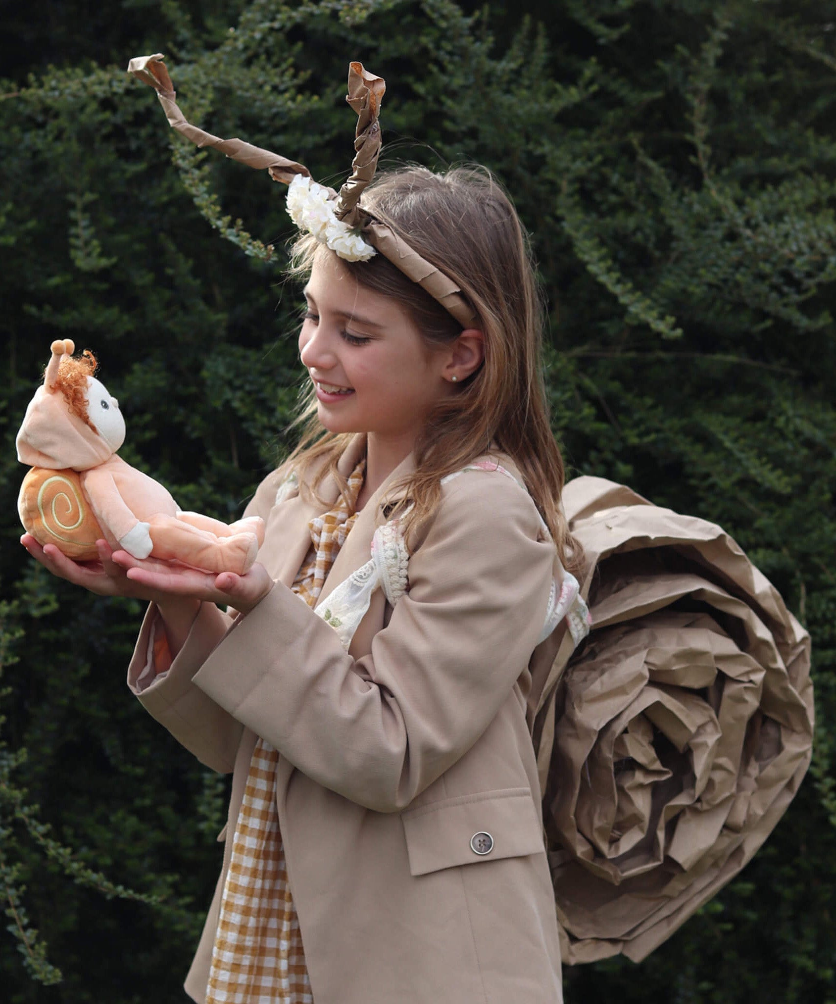 A girl dressed up in a homemade snail costume, holding Scottie Snail, the Dinky Dinkum Doll from Olli Ella.