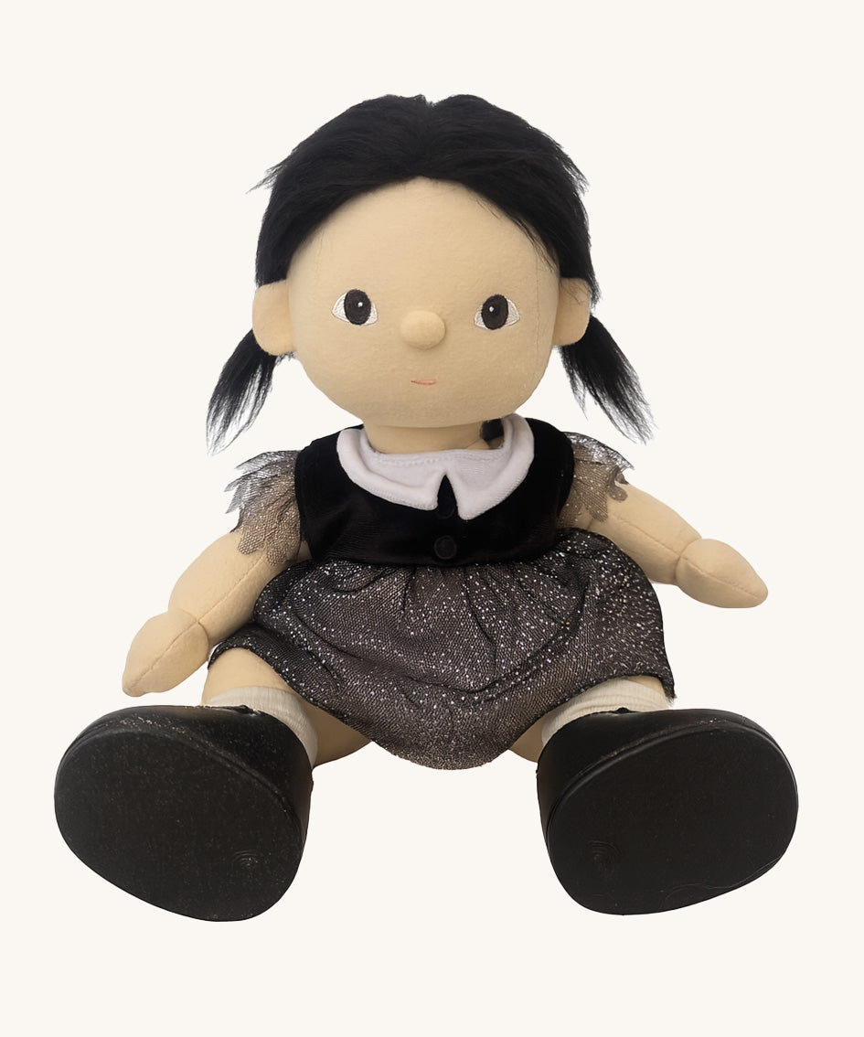 An Olli Ella Wendy Witch dream Dinkum doll in a seated position shown without her hat. A dinkum doll with a black dress, witches hat, black shoes and a magnetic broom accessory. This doll is part of Olli Ella's Halloween collection available here at Babipur.