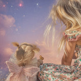 A chid sitting next to the Olli Ella Willow dream dinkum doll available at Babipur and facing a dream starry night sky