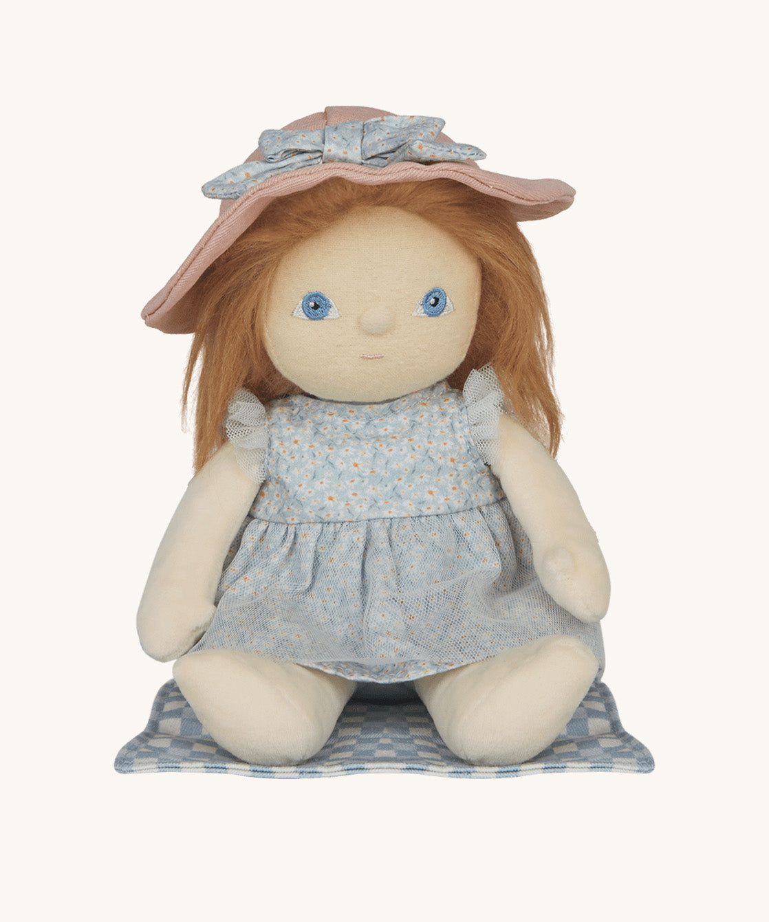 Penelope Petals Dinky Dinkum Doll sitting on her gingham picnic blanket, wearing floral blue dress and pink sunhat from Olli Ella’s Dress Me range.