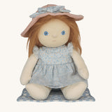 Penelope Petals Dinky Dinkum Doll sitting on her gingham picnic blanket, wearing floral blue dress and pink sunhat from Olli Ella’s Dress Me range.