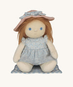 Penelope Petals Dinky Dinkum Doll sitting on her gingham picnic blanket, wearing floral blue dress and pink sunhat from Olli Ella’s Dress Me range.