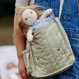 Penelope Petals Olli Ella Dinky Dinkum Doll tucked into a child’s shoulder bag, showing her long hair, soft body, and dress-up outfit.