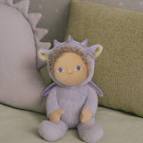 olli ella duffy the dinky dragon soft cuddly doll available at babipur. doll is sitting on a blanket with cushions in the background.