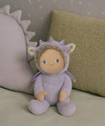 olli ella duffy the dinky dragon soft cuddly doll available at babipur. doll is sitting on a blanket with cushions in the background.