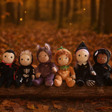 A collection of six Halloween themed Olli Ella dinky dinkums all lined up on a log. These soft toys are part of Olli Ella's Halloween collection available here at Babipur.
