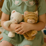 A close of a little girl holding a Olli Ella Kiki and Koda binky dolls showing their sleeping face and whisker detail. Both of these dolls are available at Babipur.