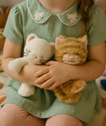 A close of a little girl holding a Olli Ella Kiki and Koda binky dolls showing their sleeping face and whisker detail. Both of these dolls are available at Babipur.