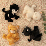 A group of Olli Ella binky kitten toy dolls lying on a floral blanket. These cuddly toys have a sleeping face and feature cute ears and whiskers. These soft dolls are available at Babipur.