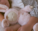 A close of a child cuddling the Olli Ella Pink Bunny Moppet Lullaby Cozy Dinkum.
