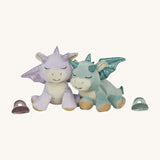 A Olli Ella volt and misty binky dragon dolls standing next to their matching magnetic pacifiers. These two dragons are available at Babipur.