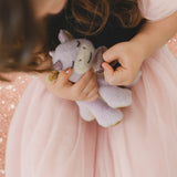 A child wearing a princess outfit and holding a Olli Ella misty binky dragon doll with the magnetic purple pacifier near the mouth. This fluffy soft toy is available at Babipur.