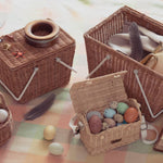 a rattan picnic basket with white handles