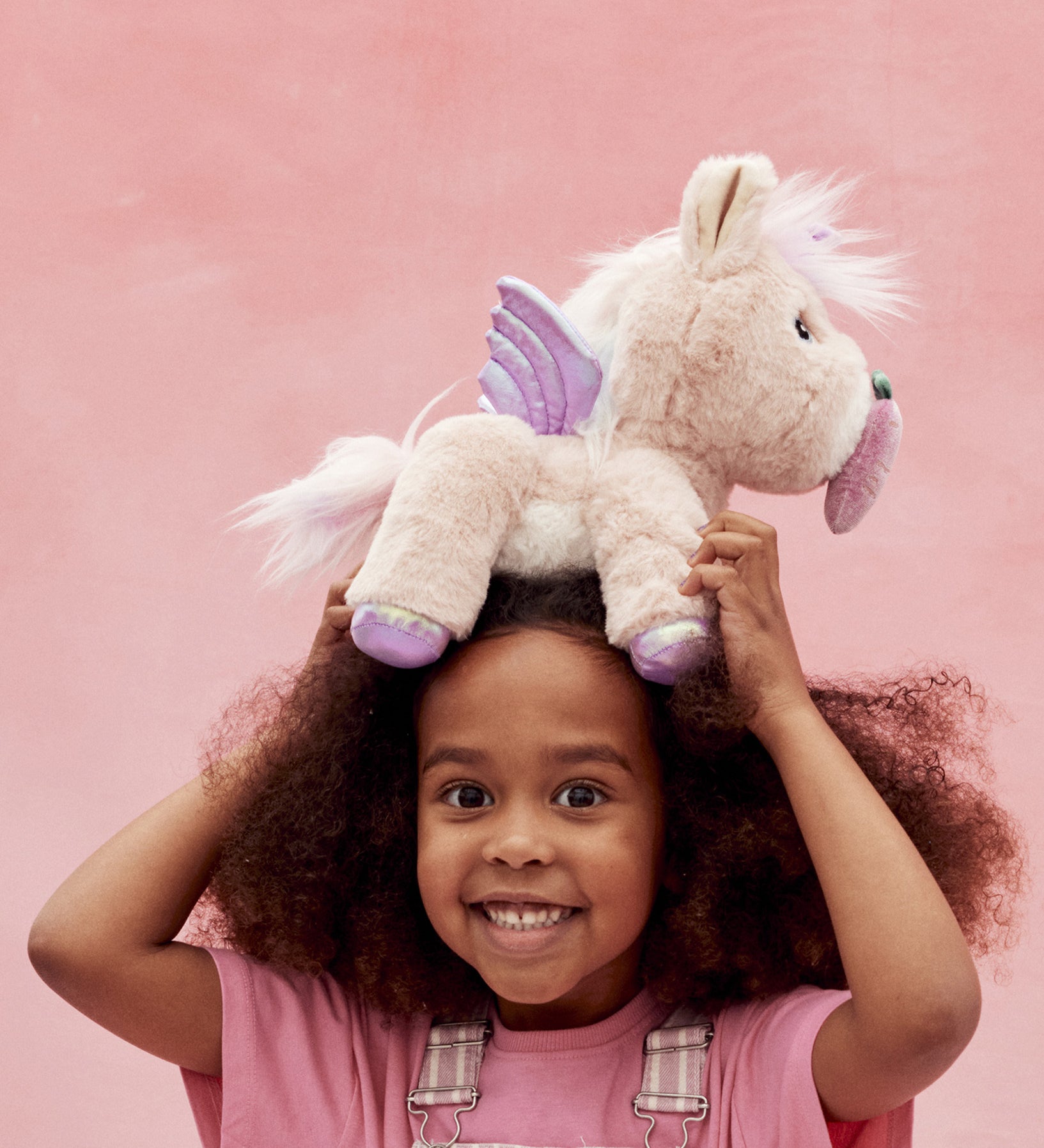 A child holding the toy unicorn above her head