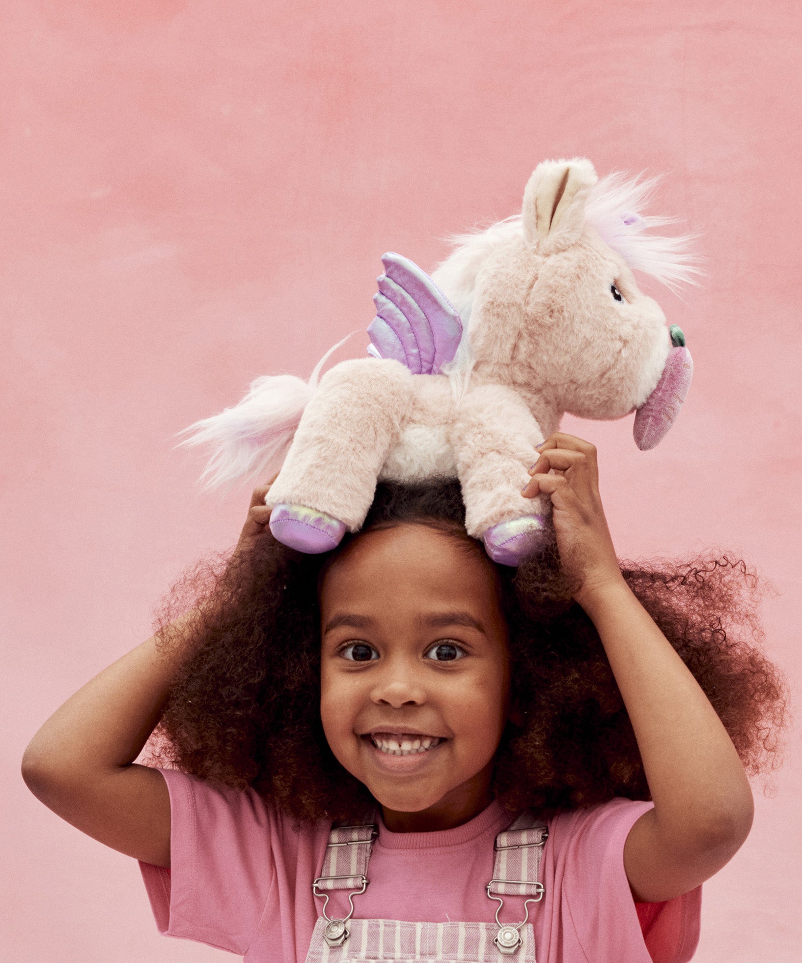 A child holding the toy unicorn above her head