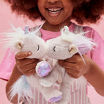 A little girl playing with the lilac and pink baby unicorn toys