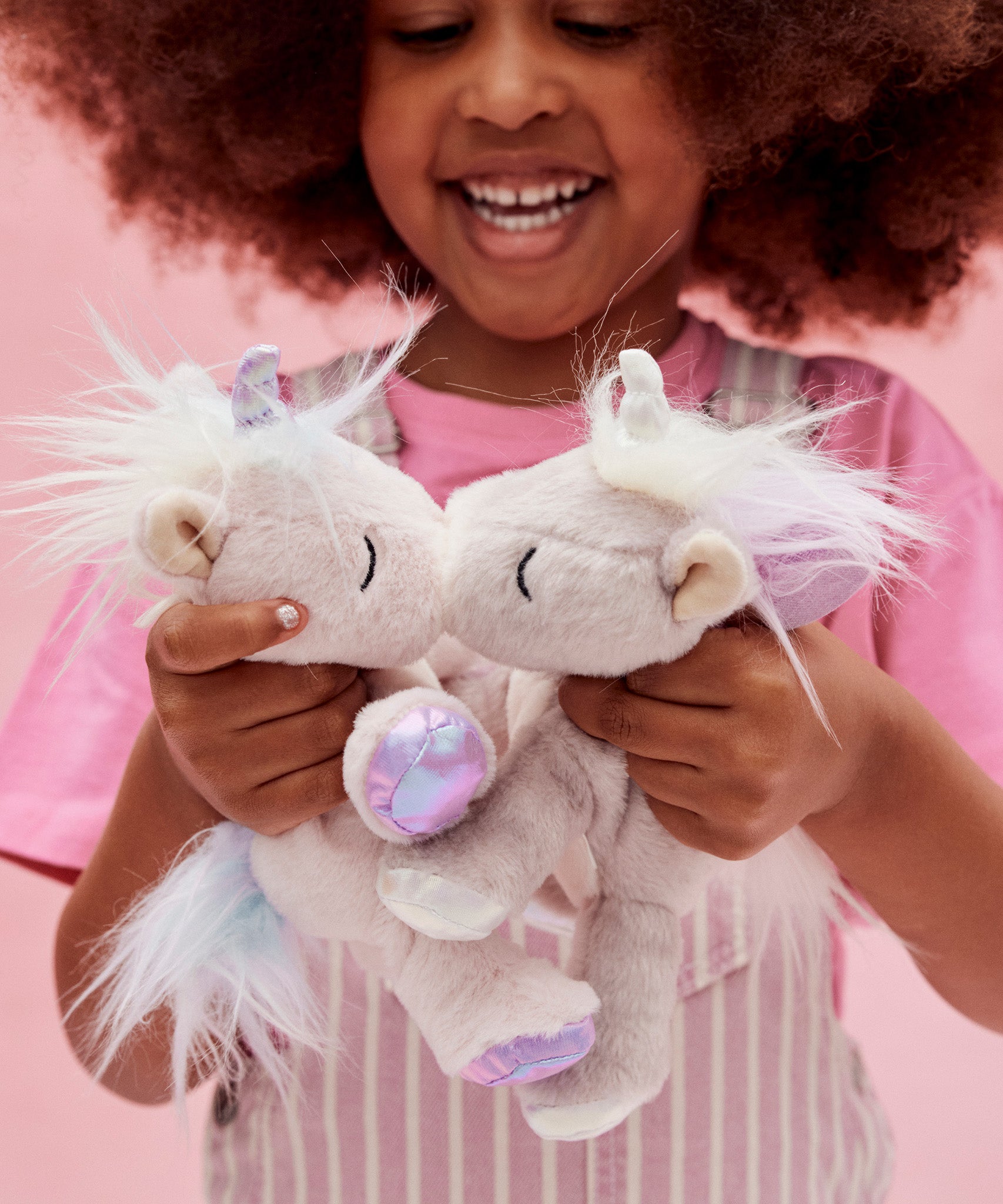 A little girl playing with the lilac and pink baby unicorn toys