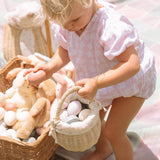 A child collecting eggs from a colourful blanket and into the Olli Ella Rattan Berry Basket with Lining – Pansy Floral.