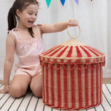 A child lifting the top off the Olli Ella Red & Straw Rattan Circus Tent Basket. This large capacity basket is perfect for use as toy storage. Olli Ella have a range of stylish storage solutions and soft toys available here at Babipur. 