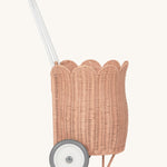 A side view of the Olli Ella Seashell Pink Rattan Petal Luggy.