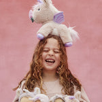 A girl with the Olli Ella Dinkum unicorn balancing on her head, and holding lots of dinky dinkums in her arms