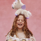 A girl with the Olli Ella Dinkum unicorn balancing on her head, and holding lots of dinky dinkums in her arms