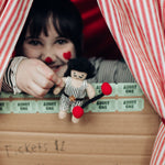 A child holding Olli Ella Holdie Circus Folk Samson The Strongman at a ticket booth stand
