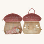 The Olli Ella Rattan Woven mushroom doll's house, with a pink spotty toadstool top. It is fully opened, and a little dozy dinkum doll is having a nap inside.