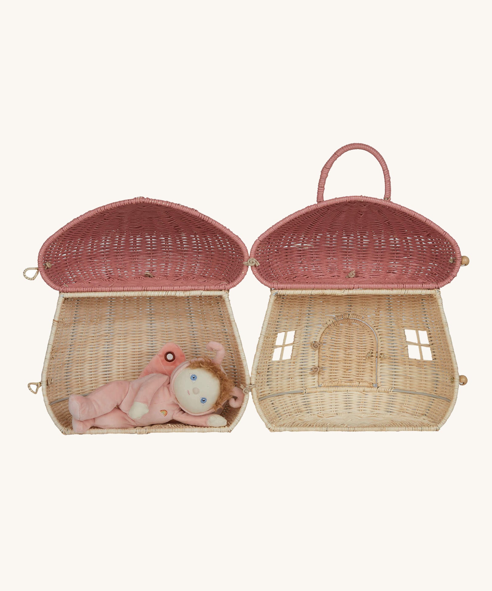 The Olli Ella Rattan Woven mushroom doll's house, with a pink spotty toadstool top. It is fully opened, and a little dozy dinkum doll is having a nap inside.