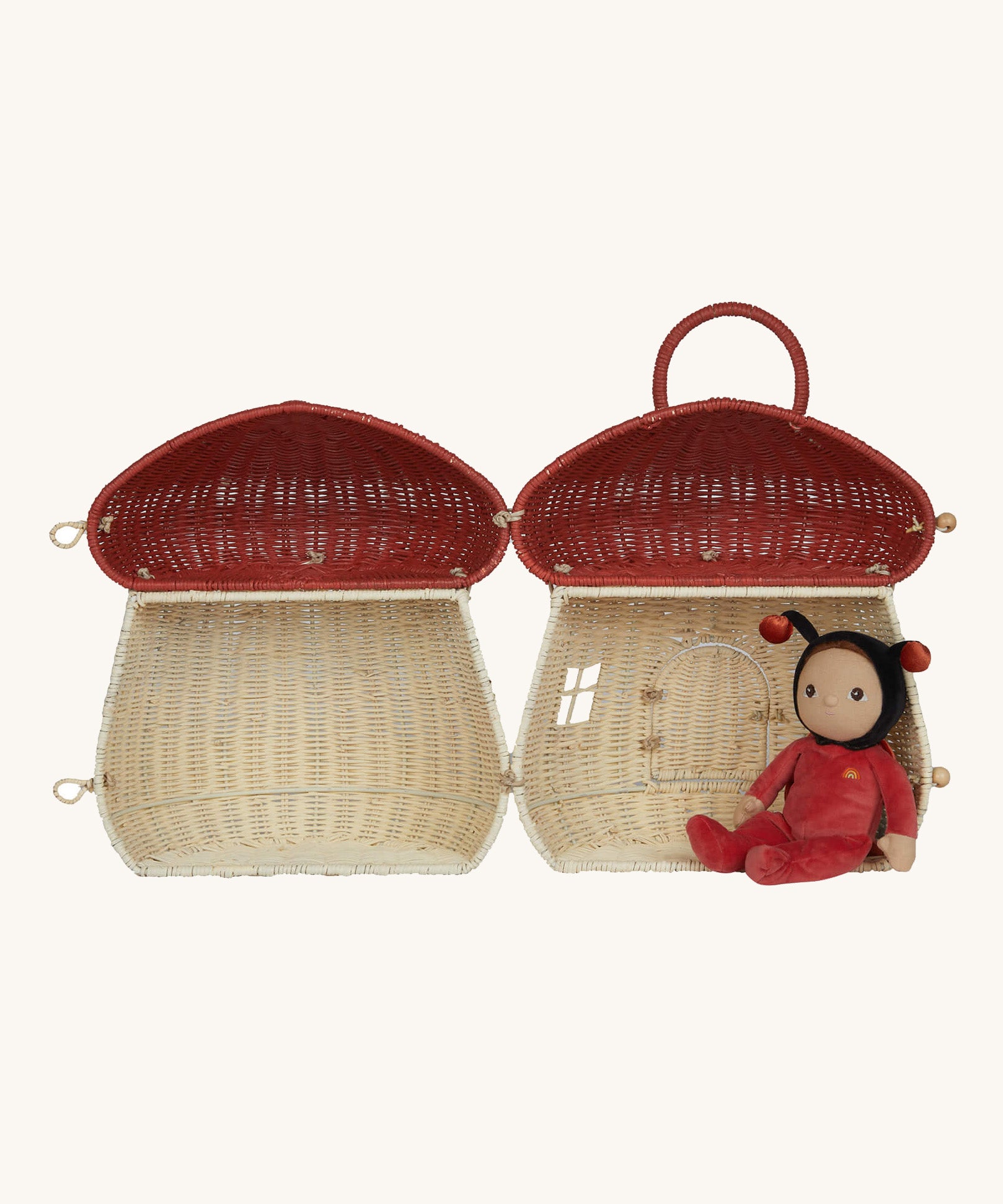 The Olli Ella Rattan Woven mushroom doll's house, with a red spotty toadstool top. It is opened all the way, and inside is a dozy dinkum doll resting. 
