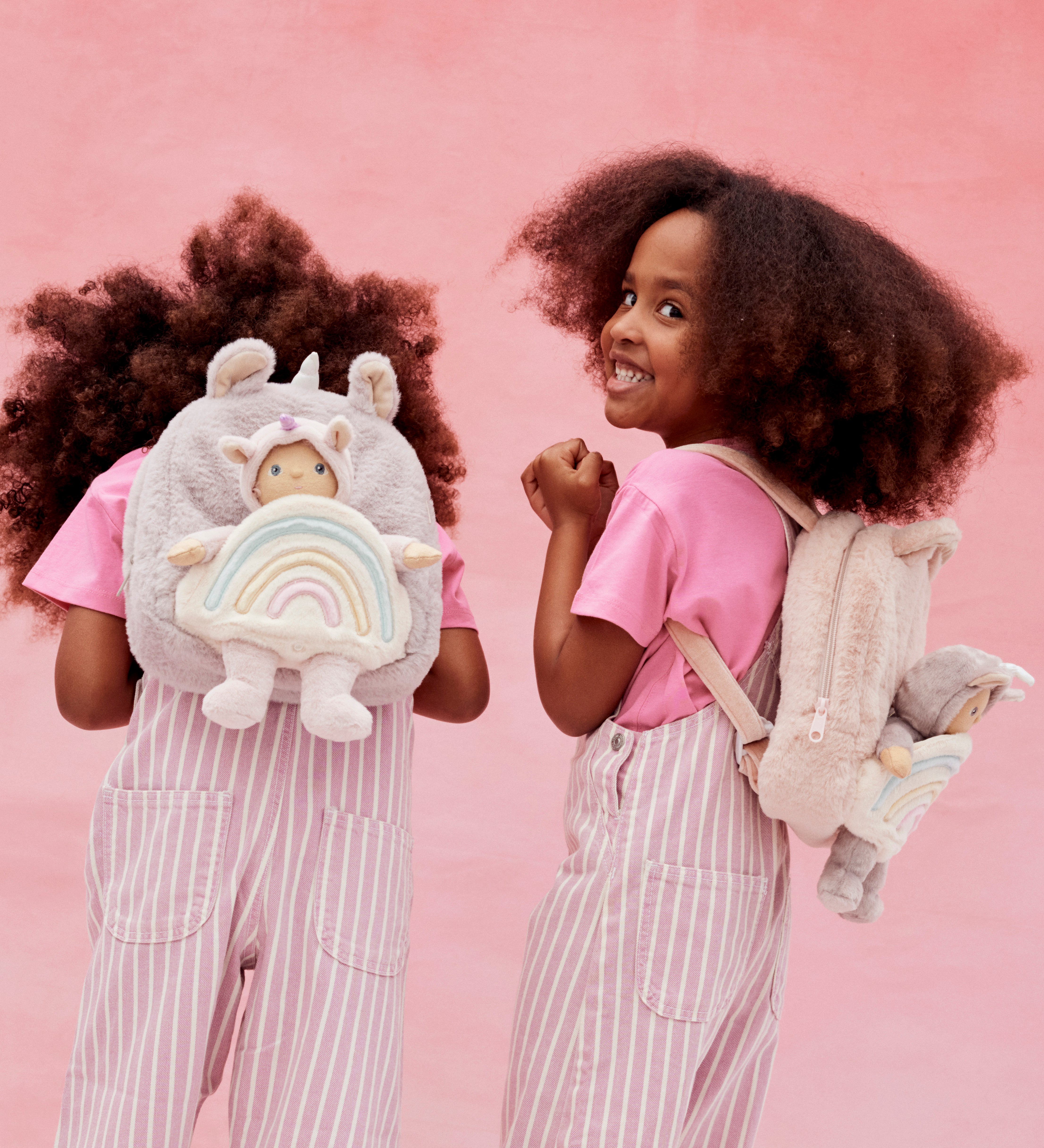 2 kids wearing the pink and lilac Olli Ella backpacks with dinky dinkum dolls on the back.