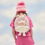 A child wearing the pink fluffy Olli Ella backpack with a dinky dinkum doll sitting in the bag.